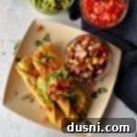Overhead shot of crispy Chicken & Cowboy Caviar Taquitos on a plate with a small bowl of Cowboy Caviar.