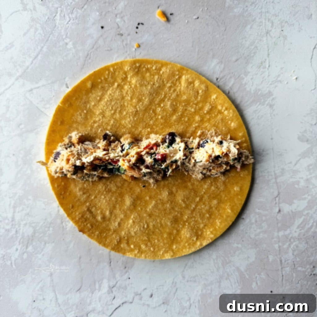 Hands mixing the rich Chicken and Cowboy Caviar filling in a bowl, preparing for taquito assembly.
