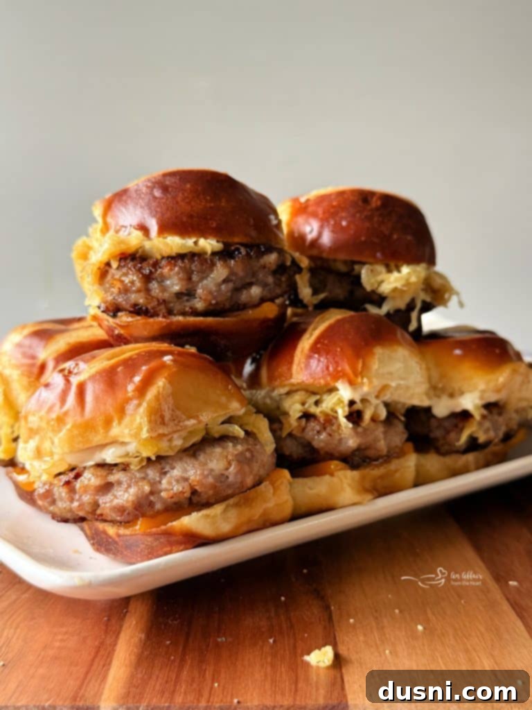 Close-up of three delicious Bratwurst Sliders on pretzel buns with melted cheddar and mustard kraut, garnished with a pretzel stick.