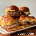 Bratwurst Sliders stacked on a white serving platter.