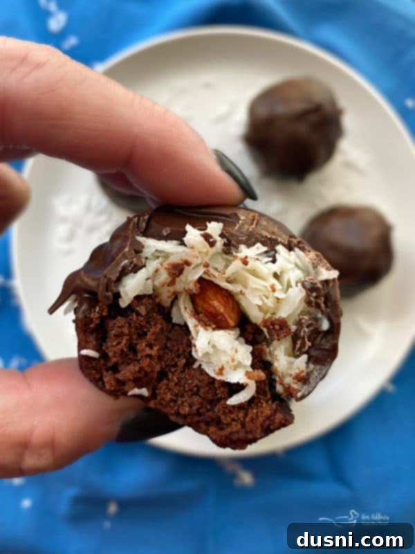 Coconut Almond Brownie Bites 8 Almond Joy Brownie Bites with a bite taken out, showing the layers of chocolate, coconut, and brownie