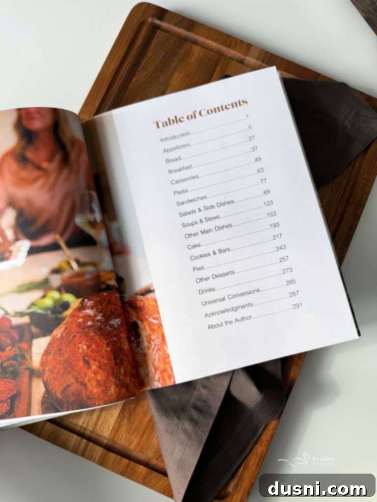 Michaela Kenkel holding her new Savor It cookbook, smiling warmly.