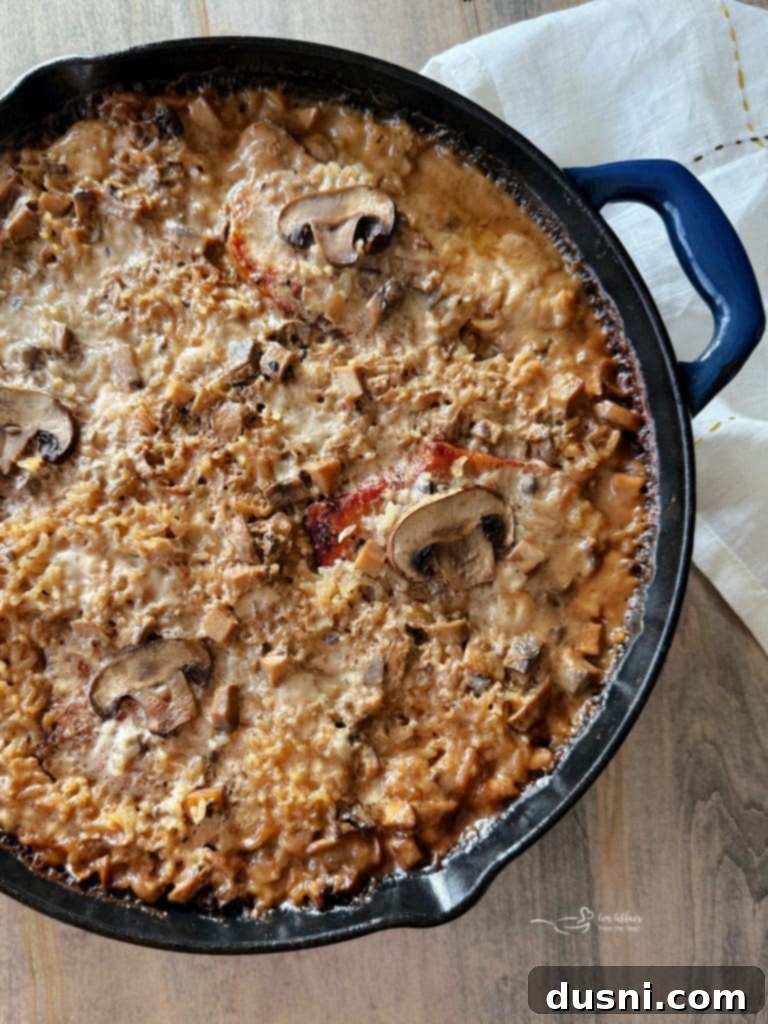 Close up of a baked No Peek Pork Chops and Rice dish, showing tender pork chops on top of fluffy rice with mushroom sauce.