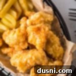 Hot Honey Glazed Crispy Popcorn Chicken 14 Close up of Hot Honey Popcorn Chicken and french fries in a parchment lined basket.