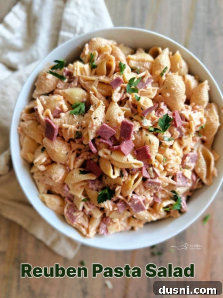 Large bowl of Reuben Pasta Salad garnished with fresh parsley, ready for a gathering.