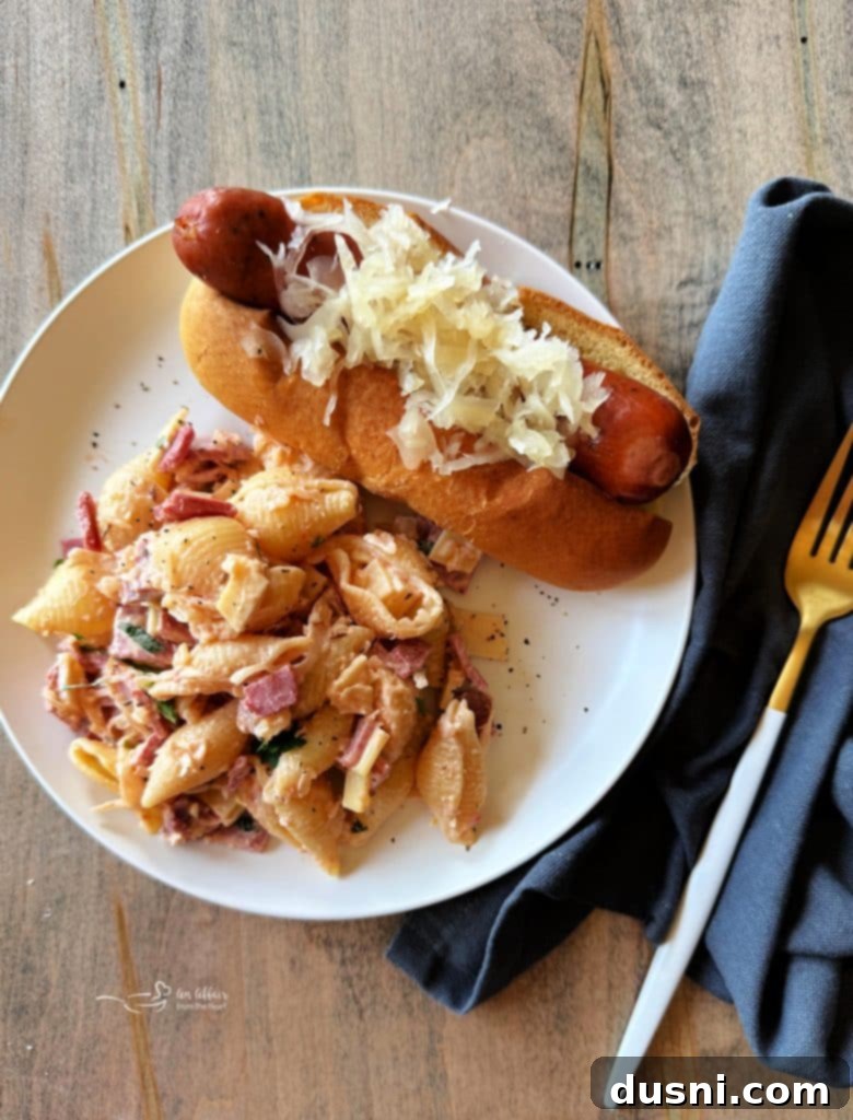 Ingredients for Reuben Pasta Salad laid out on a wooden cutting board, including pasta, corned beef, Swiss cheese, and Frank's Kraut.