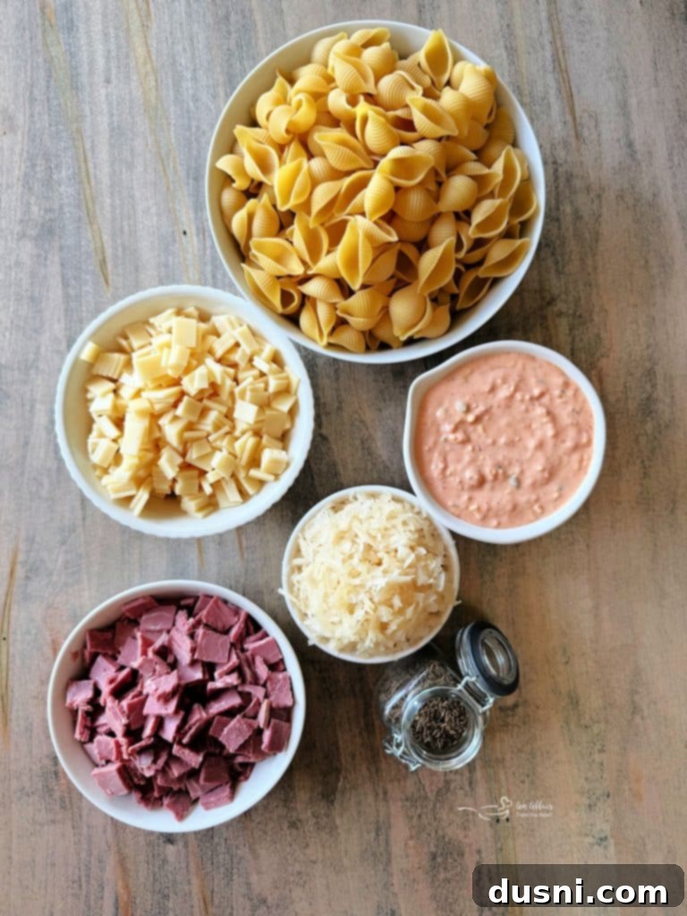Bowl of cooked pasta shells with corned beef and Swiss cheese cubes.
