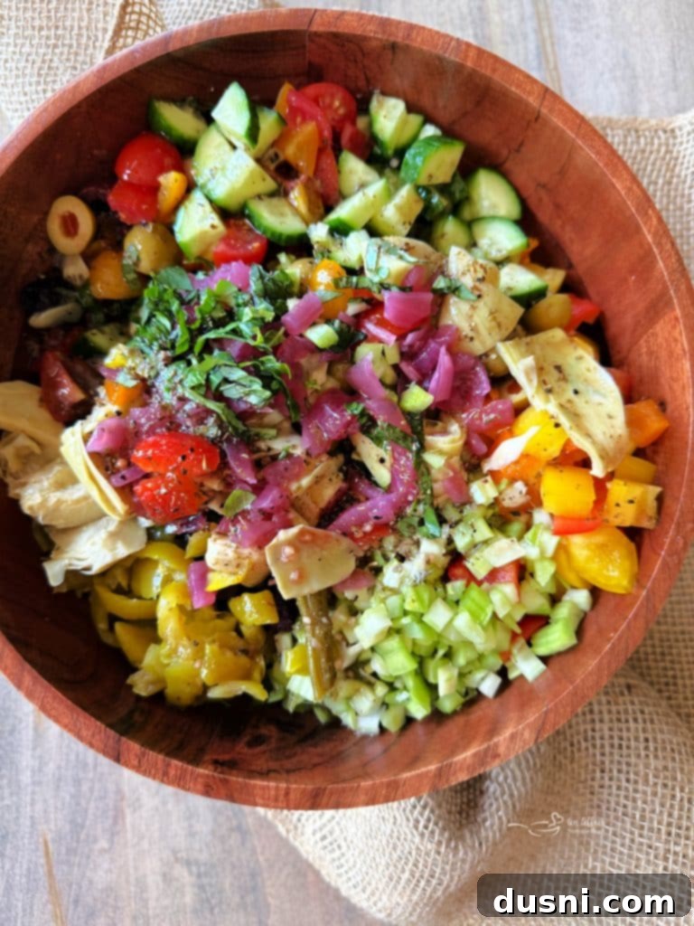 Mediterranean dressing being poured over the prepared vegetable salad