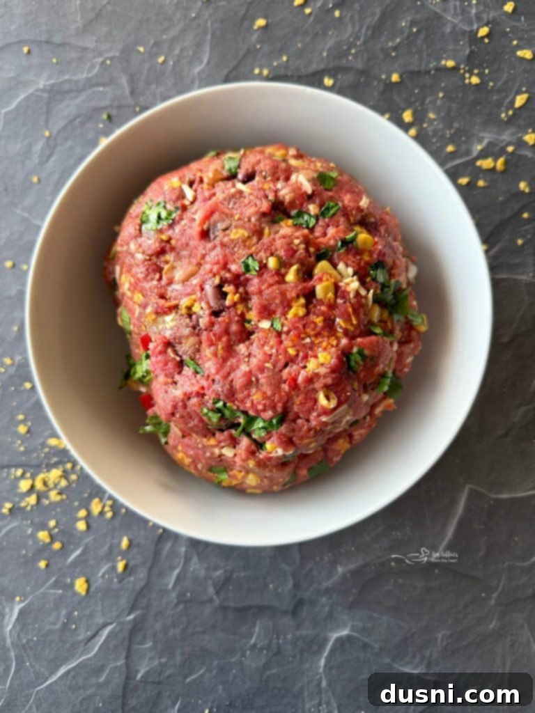 Mexican Street Burgers 10 Hands mixing burger ingredients in a large bowl.