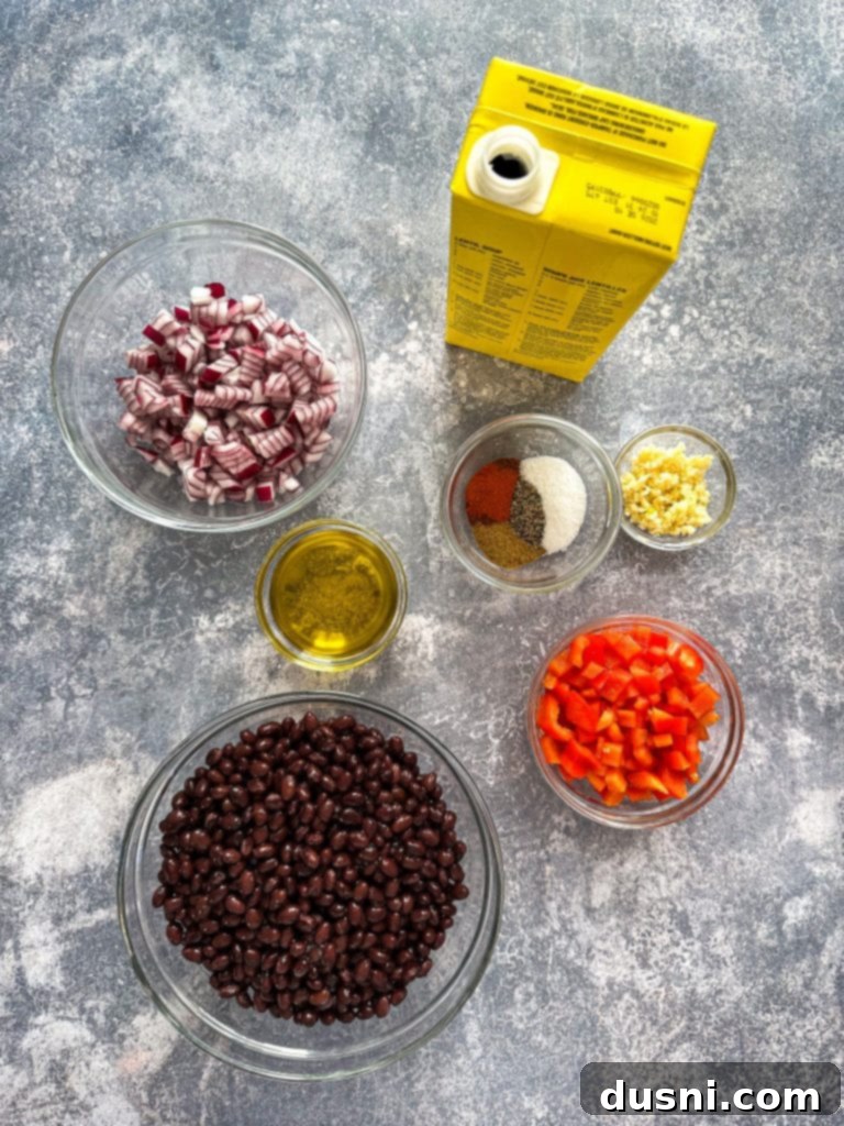 Hearty Black Bean Soup Made Simple 5 Fresh ingredients laid out for black bean soup: canned beans, red onion, bell pepper, and spices.