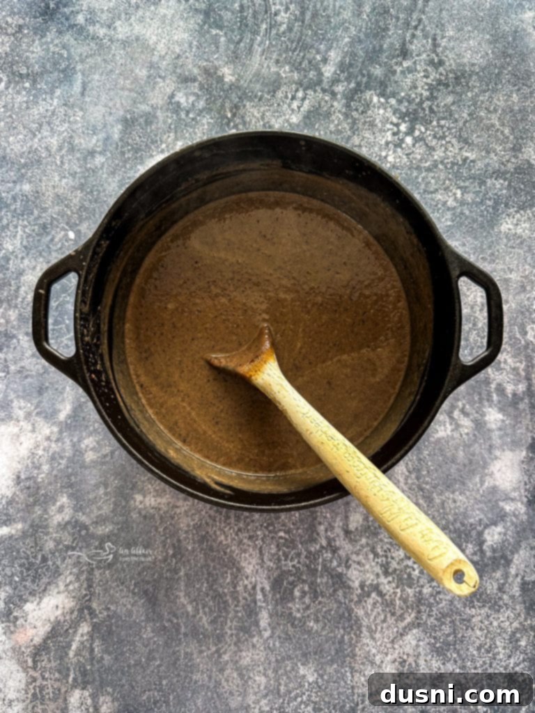 Hearty Black Bean Soup Made Simple 9 A person blending black bean soup directly in the pot with an immersion blender.