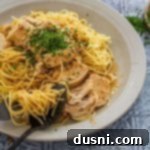 Twisting the pasta with a spoon and fork in a bowl of Slow Cooker Angel Chicken.