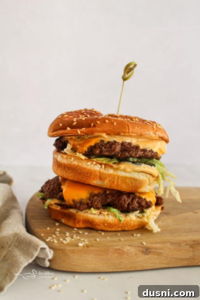 A delicious homemade Big Mac burger, layered with two beef patties, special sauce, cheese, lettuce, pickles, and onions, on a toasted sesame seed bun.