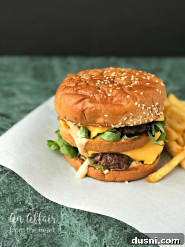 Side view of a perfectly assembled Copy Cat McDonald's Big Mac, showcasing layers of patties, sauce, and fresh toppings.