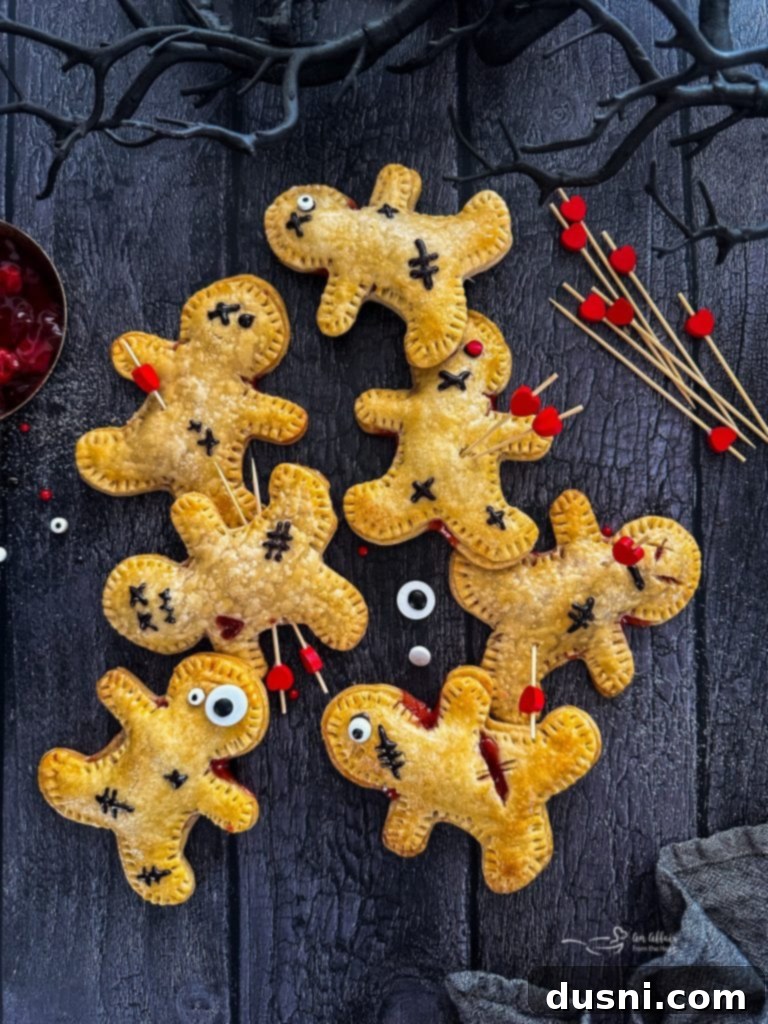 Mystic Doll Pastries 4 A tray of freshly baked Voodoo Doll Hand Pies, golden brown, with cherry filling and some initial icing decorations.