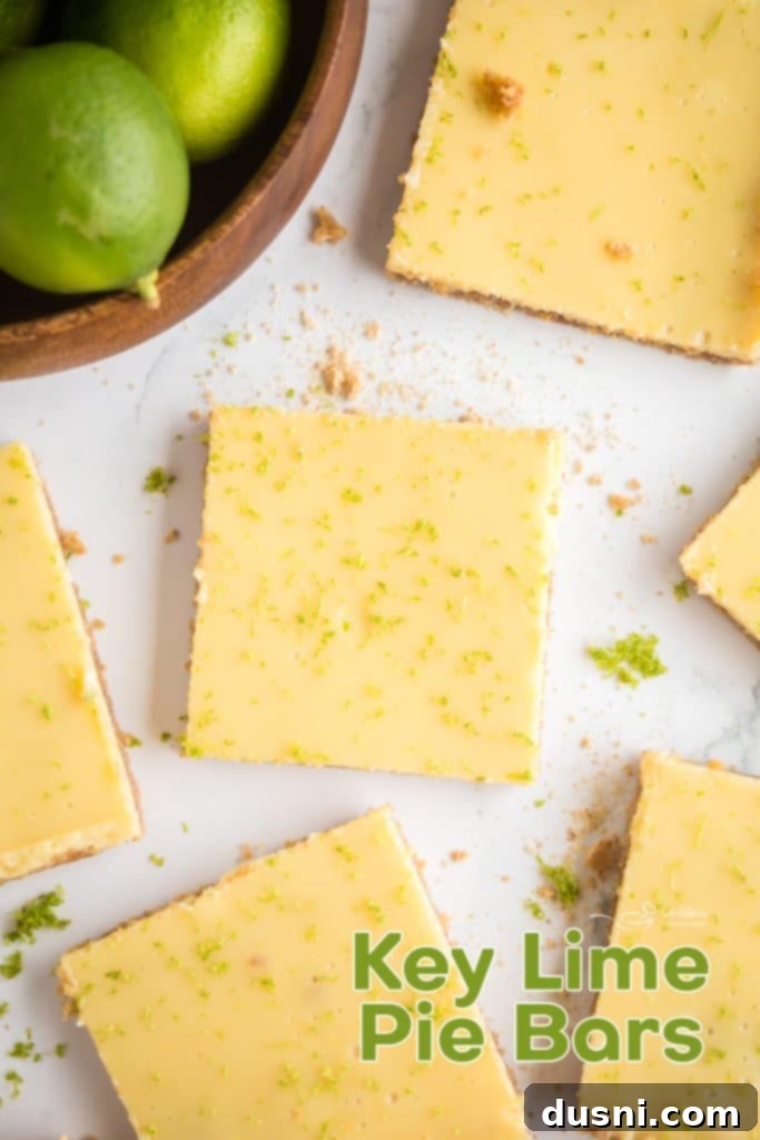 Zesty Key Lime Pie Bars 16 A large stack of Key Lime Pie Bars on a white background, garnished with lime slices.