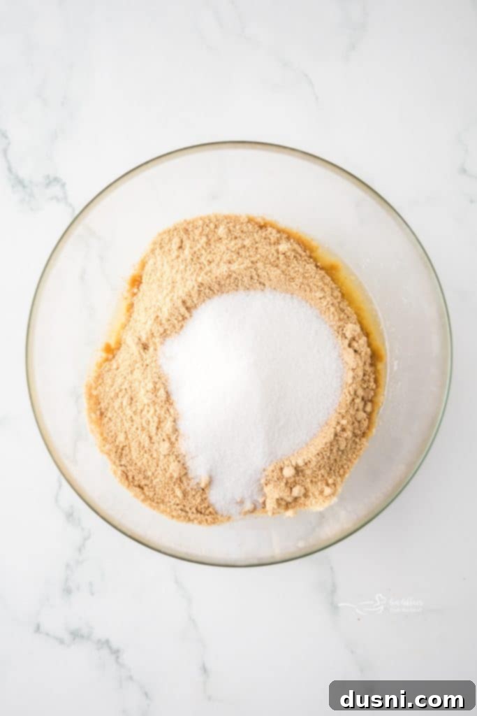 Zesty Key Lime Pie Bars 7 Melted butter being poured over graham cracker crumbs in a bowl.