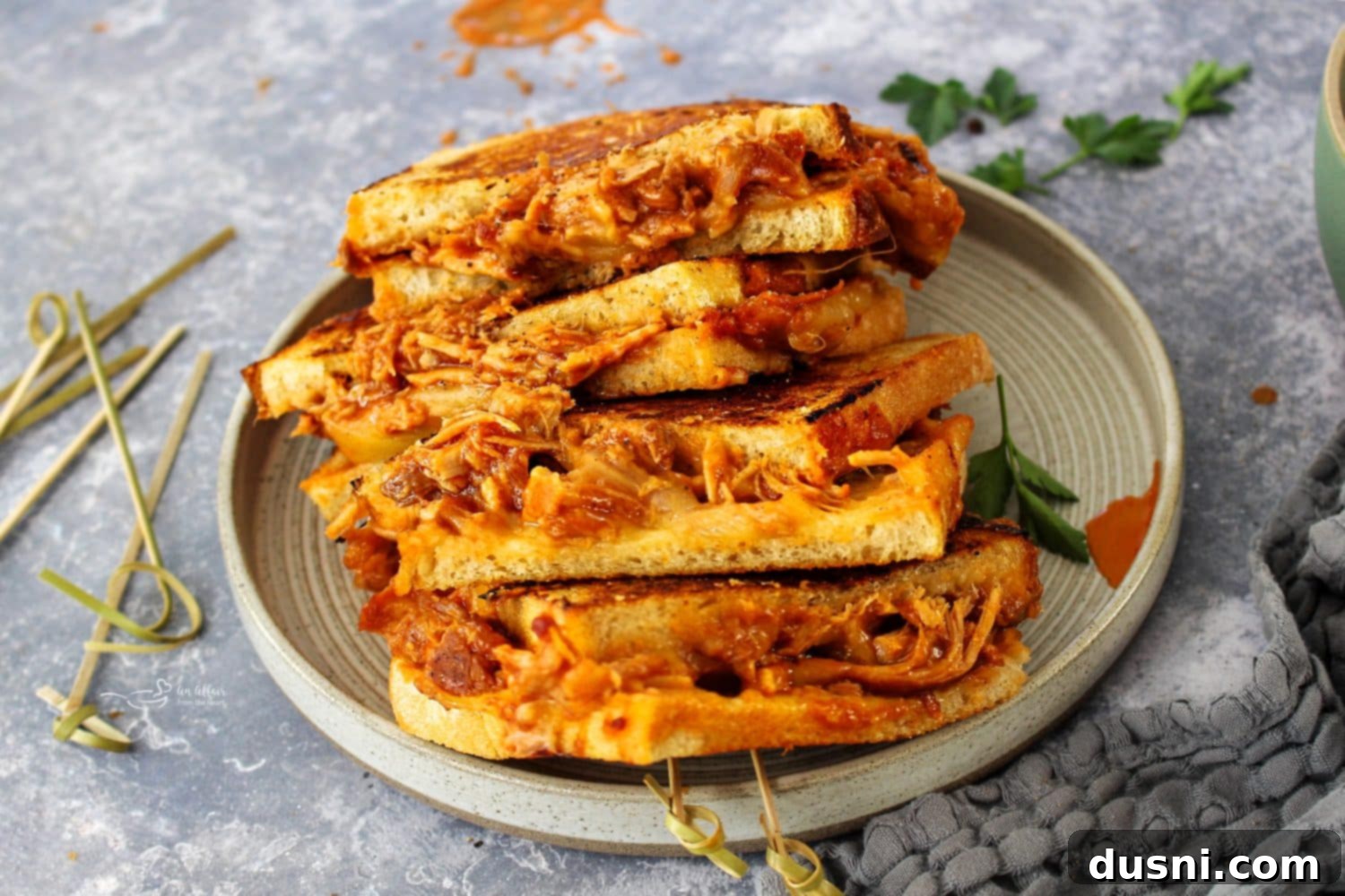Two BBQ Pulled Pork Grilled Cheese sandwiches served with a side of potato chips and coleslaw.