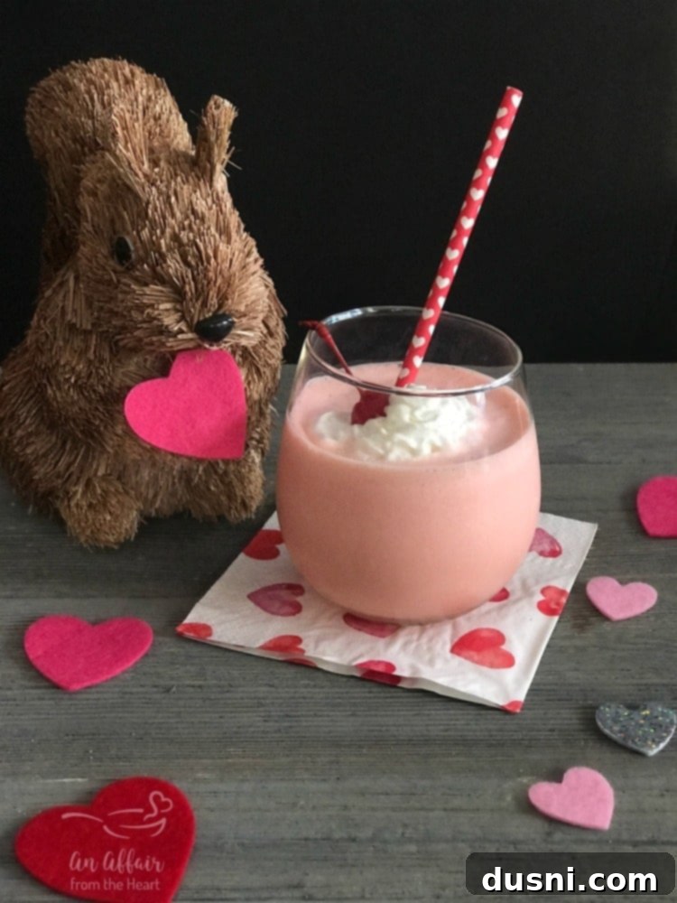 Velvet Almond Blush 19 Pink Squirrel cocktail with whipped cream and cherry on top, sitting on a table.