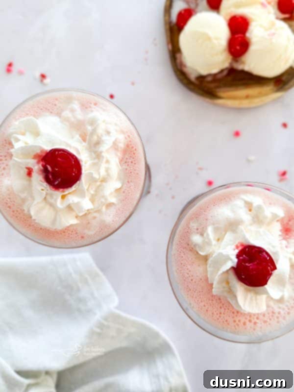 Velvet Almond Blush 3 Two Pink Squirrel cocktails garnished with whipped cream and cherries.