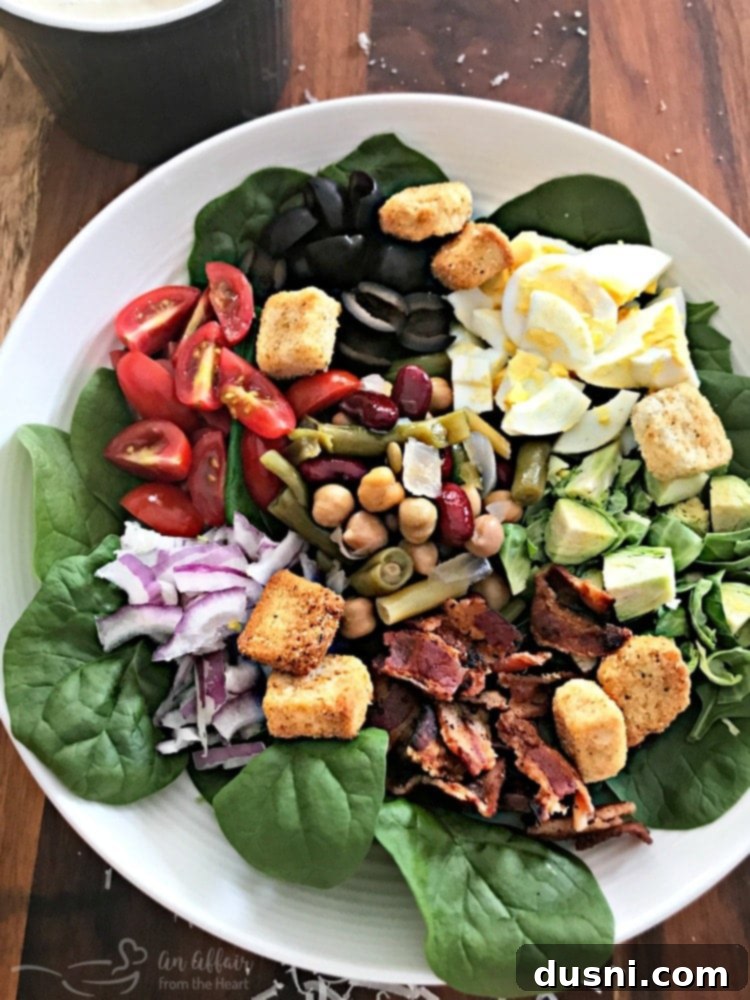 Beautifully plated Loaded Spinach Salad, ready to be enjoyed with the creamy dressing