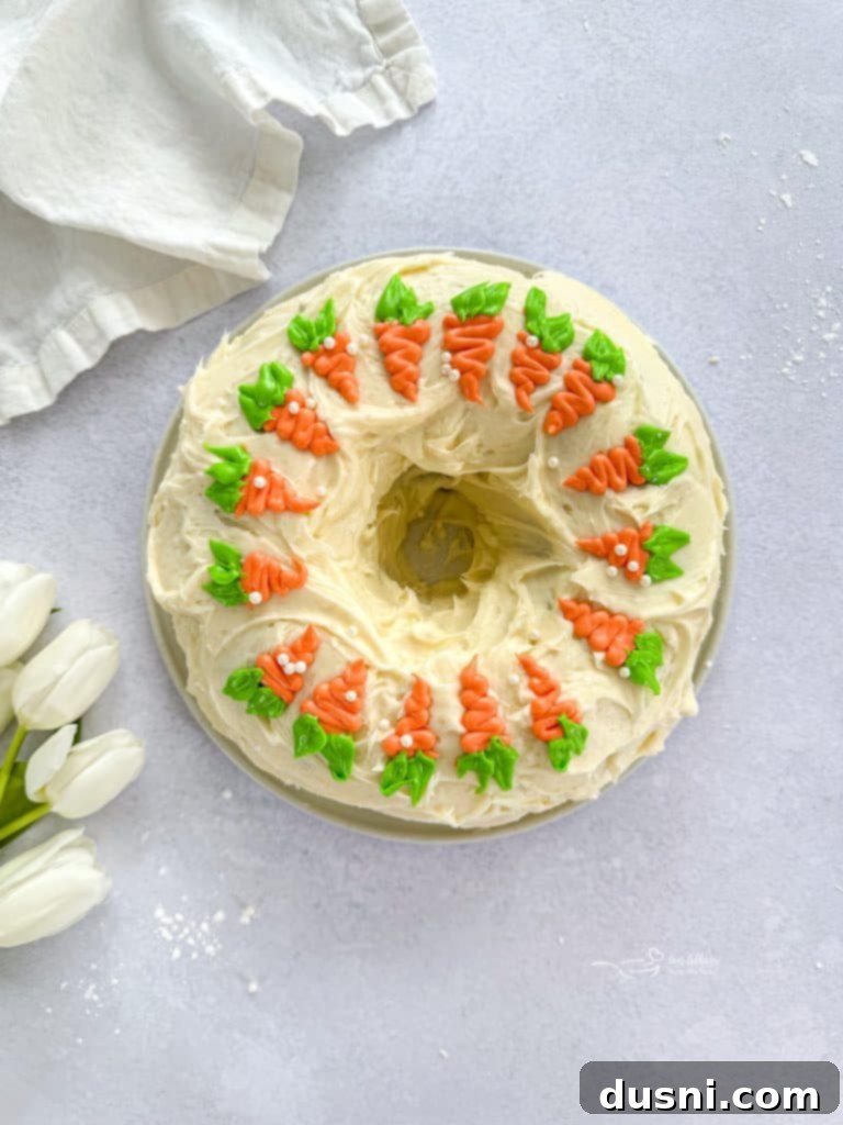 Carrot Bundt Cake fully frosted with cream cheese frosting and decorative carrot toppings.