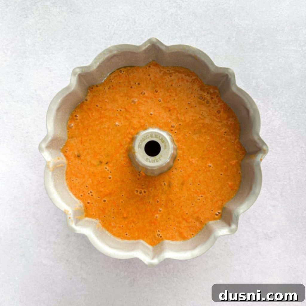 Freshly grated carrots and golden raisins being folded into the cake batter.