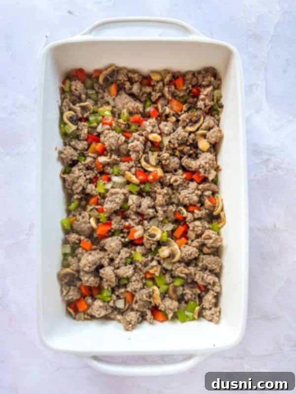 Sausage and vegetable mixture spread over crescent roll dough