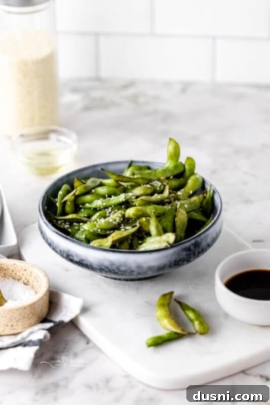 Air fryer basket filled with seasoned edamame beans