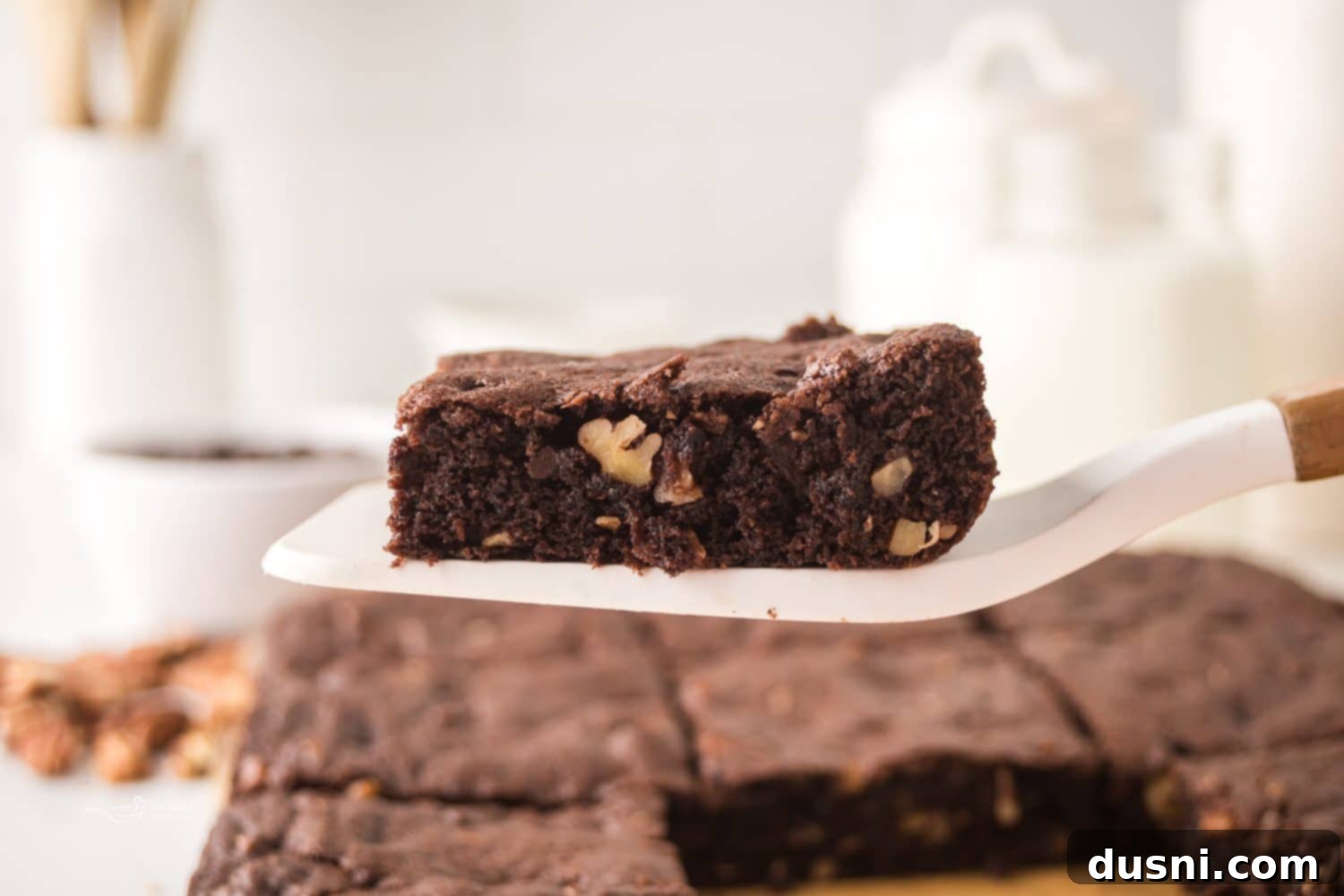 A close-up of a pan of warm pecan brownies, showing the fudgy texture and scattered pecans.