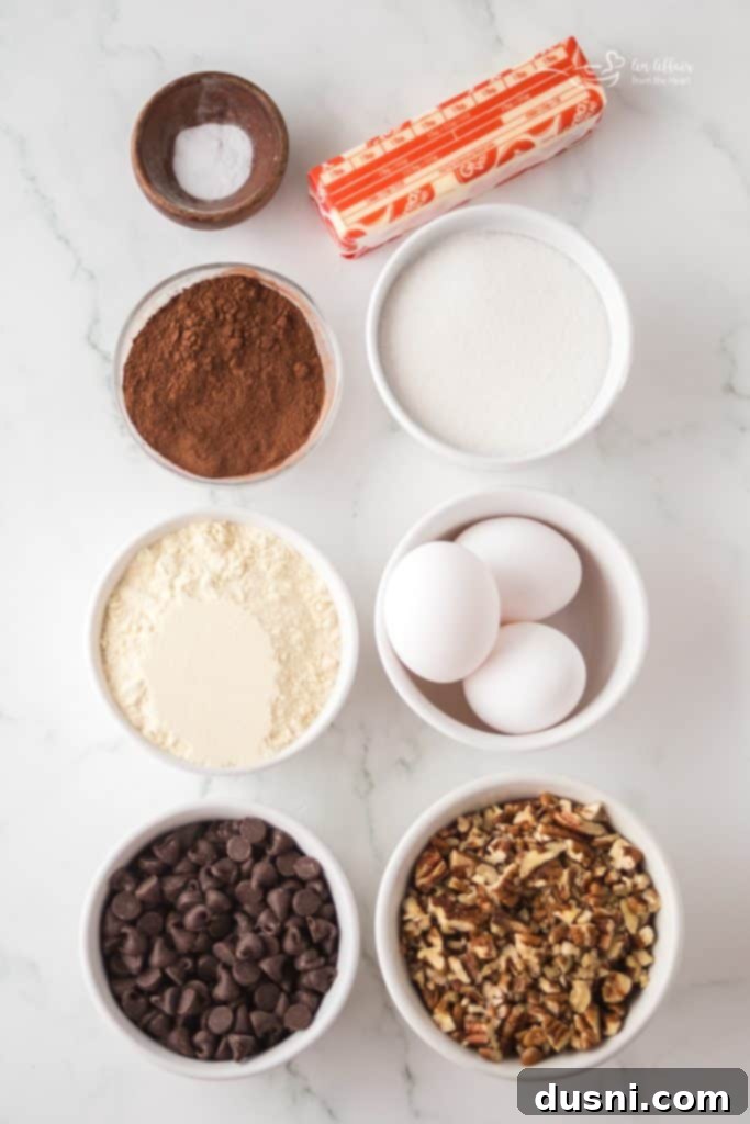 A warm pecan brownie with melted chocolate chips, sitting on a white plate with a fork.